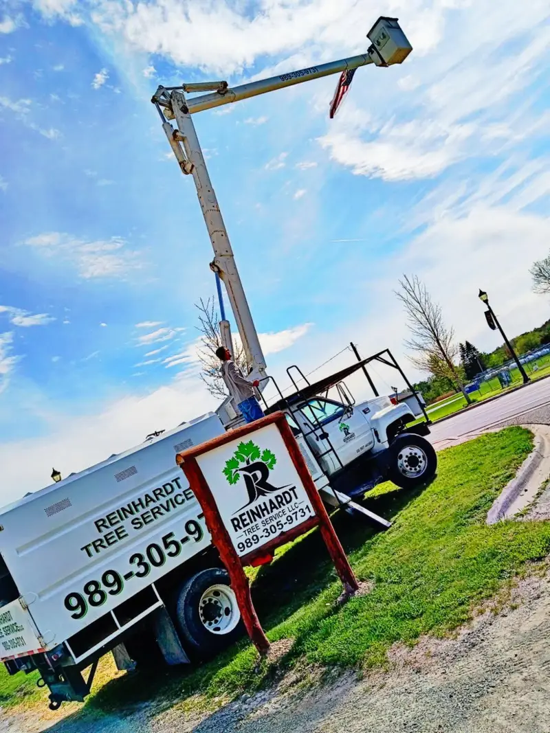 Bucket truck: boom at full height beside the roadside sign